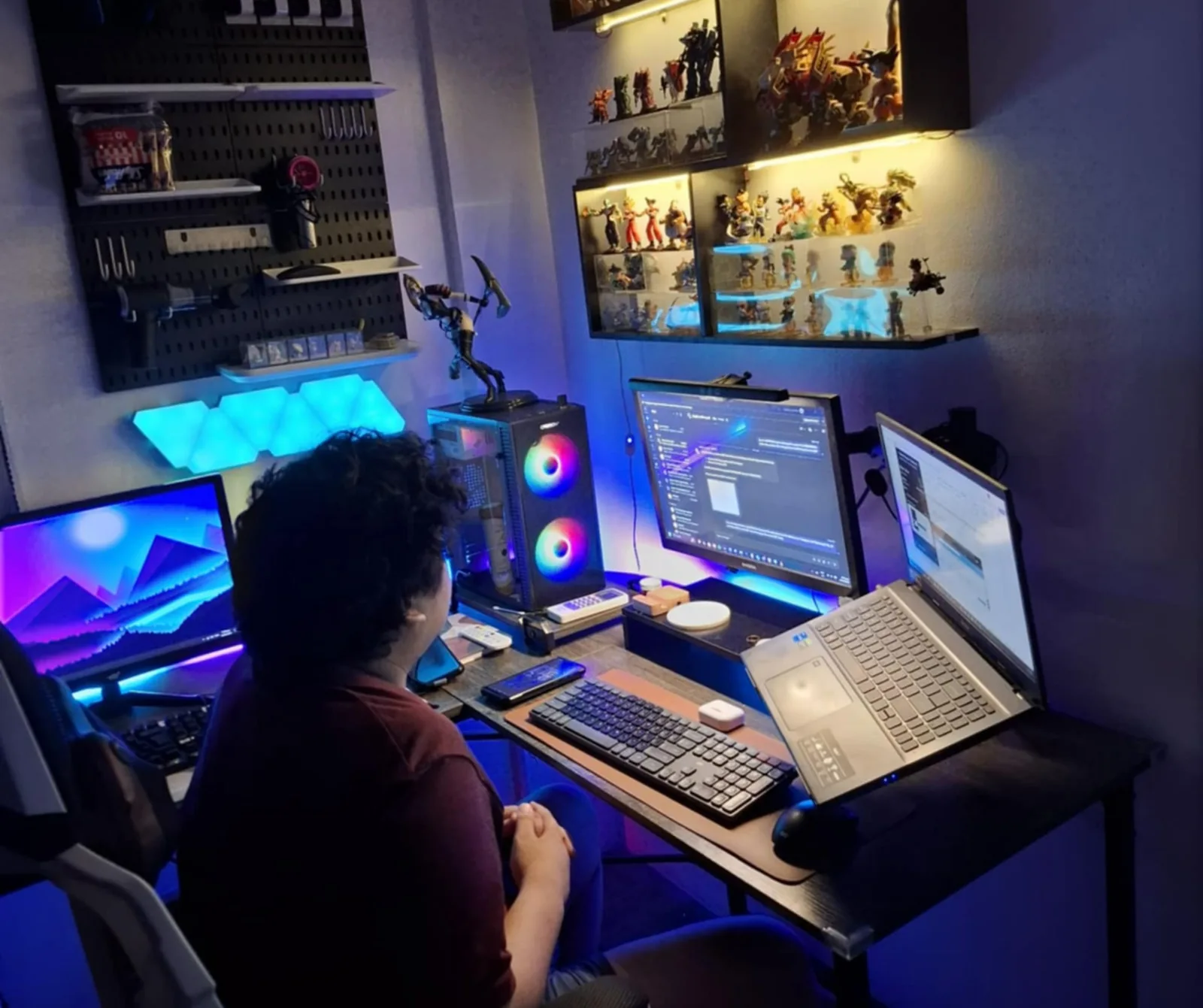 Alex seated at his desk with multiple monitors and a laptop